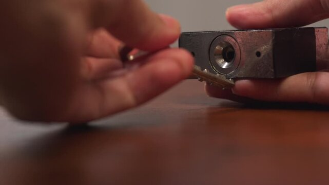 Close up of woman hands failing to insert wrong key into metal padlock on wooden desk, giving up in frustration, mistake concept.⁠