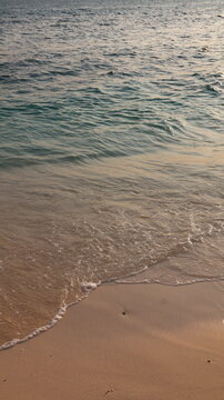 Receding wave forms a V-shaped foam edge on smooth beach sand