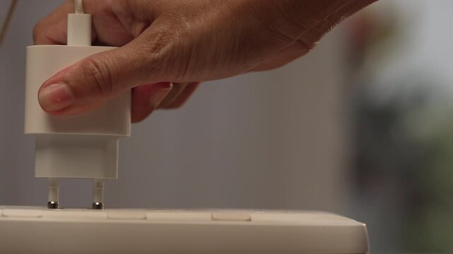 Close up on left side with copy space of woman hand pushing adapter into power strip on desk until plugged in, solution concept.
