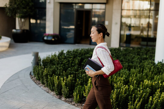 Korean woman walking confidently through a modern cityscape in the afternoon