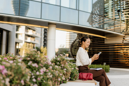 Korean woman enjoys a sunny day while interacting on her smartphone