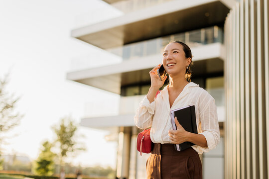 Korean woman smiles while talking on her phone in a modern city setting