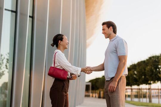 Joyful encounter between friends outside a modern building in the golden hour