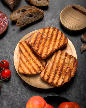 Toasted bread slices with cured Spanish ham, fresh tomatoes, and grated tomato sauce on dark surface, traditional healthy Mediterranean breakfast