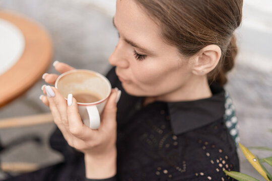 Brunette woman drinking latte during daytime cafe break