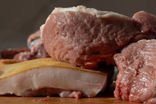 Gritty close-up of raw pork with bone and fat in a home butchery setting
