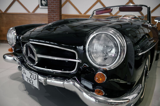 Close-up of classic car 1960s Mercedes-Benz 190 SL features a glossy black body and a chrome grille with a large three-pointed star.