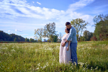 Fototapeta premium mature couple expecting baby posing together in wild flower meadow in summer