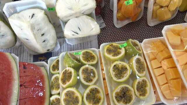 Fresh sliced watermelon, passion fruit, and custard apple at a Vietnamese street market. Symbolizes healthy eating and local produce. Ideal for food and travel content