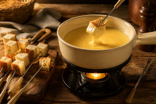 Ceramic fondue pot with melted cheese and bread skewers on rustic table, cozy cheese fondue dining concept