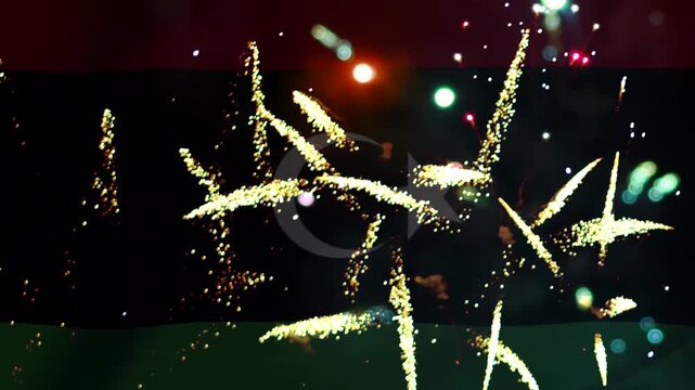 Bright golden fireworks exploding in the night sky over the national flag of Libya