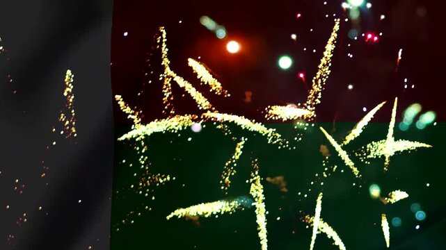 Bright golden fireworks exploding over a dark red and green wavy flag background