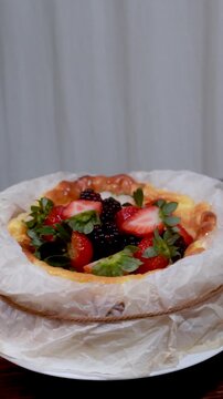 Basque cheesecake decorated with berries spinning on a wooden table