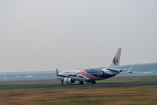 Tangerang, Indonesia - August 22, 2026: Malaysia Airlines Boeing 737 MAX 8 rolls along the runway during landing under a hazy sky at Soekarno-Hatta International Airport.