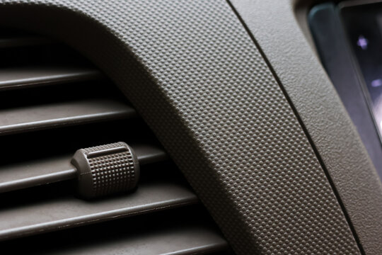 Car air vent, textured dashboard, close up interior detail, black plastic, modern vehicle ventilation
