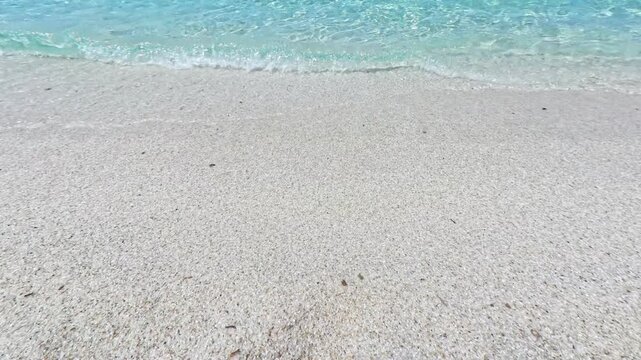Overhead shot of unique quartz pebble sand at Is Arutas Sardinia meeting crystal clear turquoise Mediterranean water