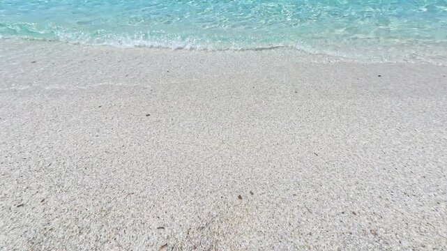 Overhead Dolby Vision shot of quartz sand at Is Arutas Sardinia meeting transparent turquoise Mediterranean sea