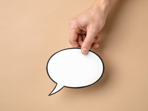 Hand holding a blank speech bubble for communication and message concept, isolated on beige background