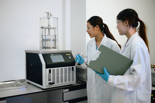 Two Female Scientists Operating a Freeze Dryer Machine in a Modern Laboratory
