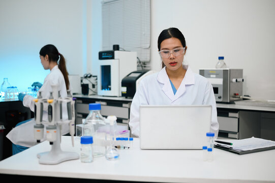 Asian Female Scientists Working in Modern Research Laboratory with Equipment and Laptop