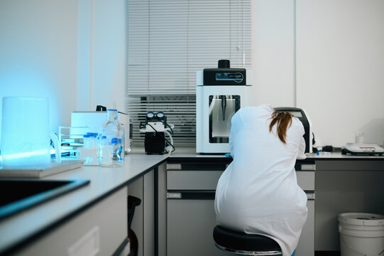 Exhausted Female Scientist in White Lab Coat Working at Laboratory Bench with Scientific Equipment and Blue UV Light
