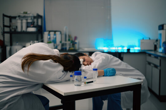 Exhausted Female Scientist Sleeping on Laboratory Desk Surrounded by Sample Vials and Equipment