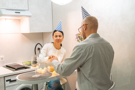 Couple Kitchen Birthday Celebration: Happy mature couple celebrating birthday with cake in modern kitchen.