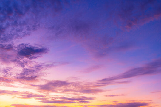 Vibrant Purple and Orange Sunset Sky with Clouds,A breathtaking, colorful sunset sky painting the heavens with vibrant shades of purple, deep violet, and warm orange. Scattered clouds create texture.