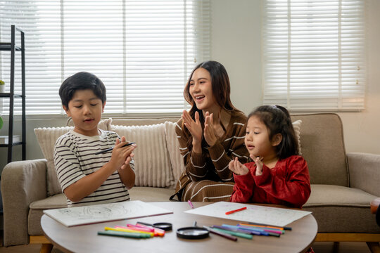 Asian mother teaching children drawing in living room