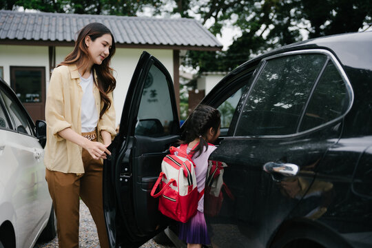 Mother helping child getting into car for school