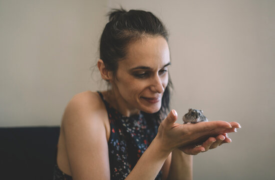 Smiling woman gently holding a small pet hamster in her hands