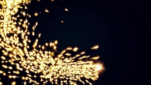 Magical stream of golden, sparkling particles and glowing star shapes swirling and flying across the screen on a dark background, creating a festive and celebratory atmosphere