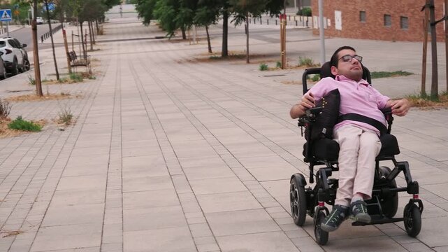 Disabled man riding an electric wheelchair on a sidewalk