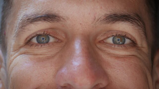 Confident male eyes look straight at camera with calm smile and control. Focused gaze and facial detail express self assurance inner balance and emotional stability in modern cinematic close up.