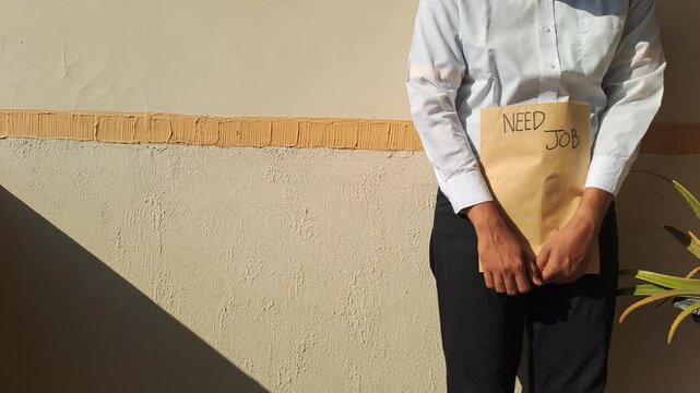 A job seeker in a white shirt gesturing toward a brown envelope with a handwritten need job text. Unemployment, career, and hiring stock video footage.