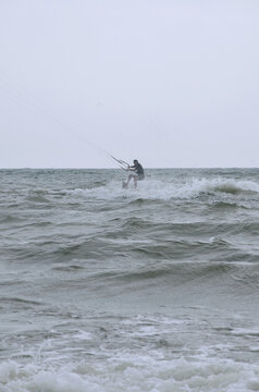 Man riding a kite surfing on the waves of ocean In windy summer day. Summer , vacation near the sea ,sport and hobby.