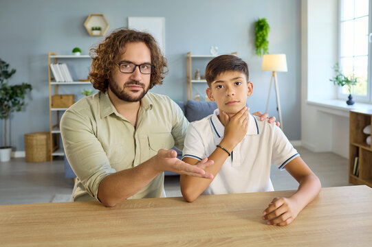 Boy and man in speech therapy lesson. Adult coach guides articulation as the child touches his throat to improve pronunciation at a desk in a bright room. Concept shows speech therapy learning.