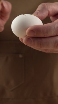 Cooks hands break the egg with knife for baking.