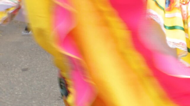 An unrecognizable woman dances a traditional dance in a yellow dress during a cultural parade at the San Juan and San Pedro Festival in Neiva, Huila, Colombia. Concept of Colombian culture