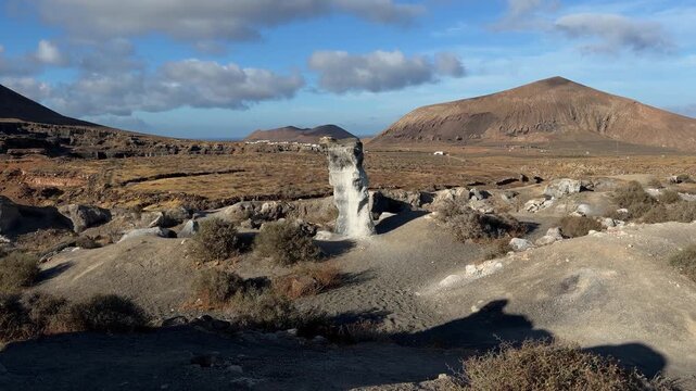 Teguise, Spain . Unique rock formations in a volcanic landscape with distant hills and blue sky, showcasing natural geological features in a remote area