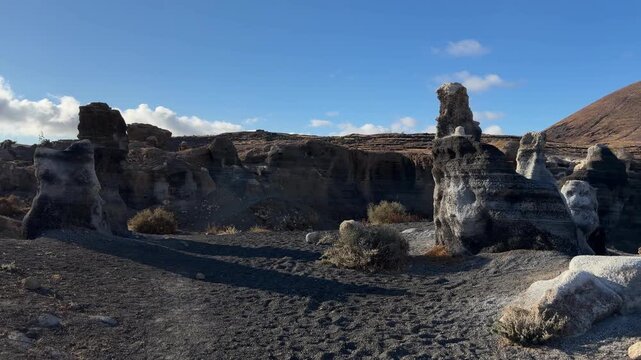 Teguise, Spain . Unique rock formations in a volcanic landscape with distant hills and blue sky, showcasing natural geological features in a remote area