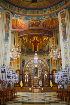 Magnificent church interior with an iconostasis, frescoes, golden chandeliers, embroidered textiles and Ukrainian flags.