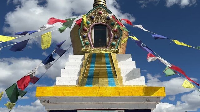 Russia - August 12, 2025: Tibetan stupa with colorful prayer flags fluttering in the wind under a clear blue sky, highlighting intricate architectural details