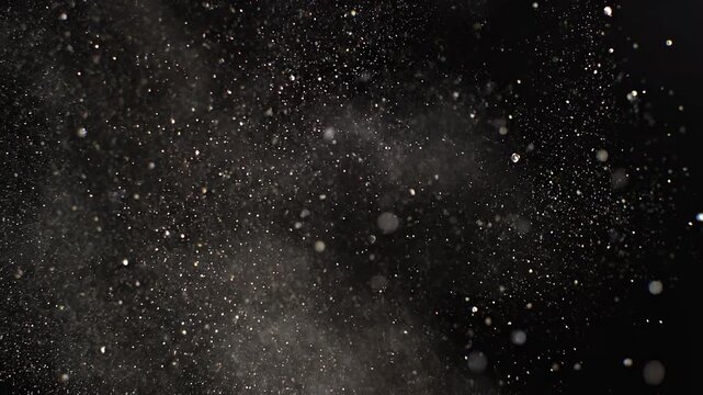 Fine white powder particles exploding and dispersing in slow motion against a dark background with cinematic lighting