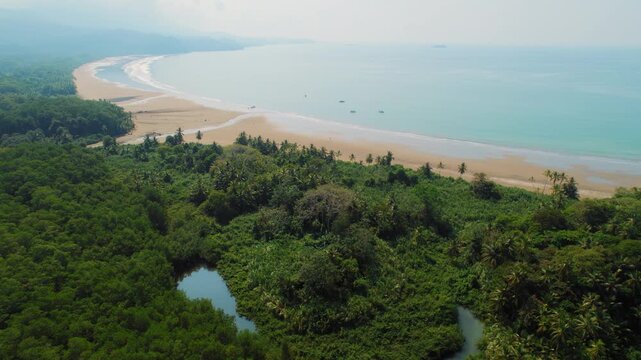 Small river flows into the ocean through tropical forest in Costa Rica