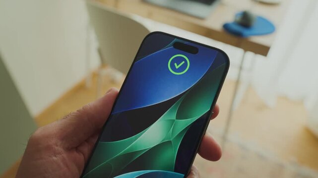 Hand holds smartphone with face recognition technology unlocking the device. Person using mobile phone with face unlock using biometrics to open system and enable access analyzing facial features