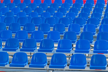 Fototapeta premium Bright blue stadium seats waiting for fans during an exciting sports event under the sun