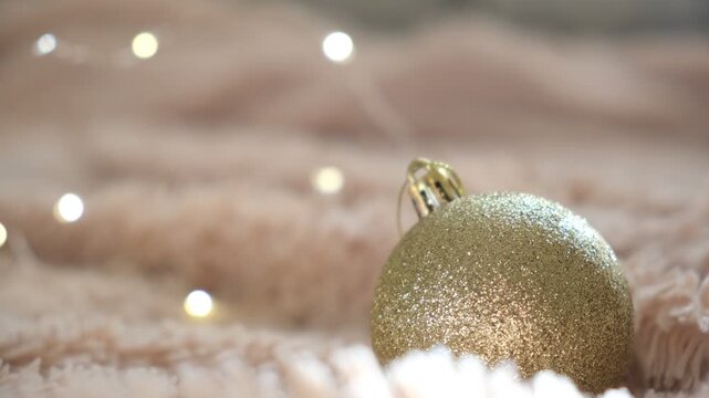 New Year and Christmas background. Golden and beige colors. Golden Christmas decorations, glittering ball on fluffy plaid, fireplace. Cozy home, waiting celebrating. New Year celebration concept.