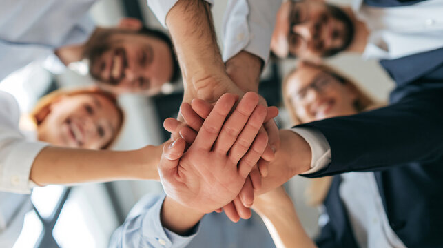 Business team putting hands together, showing unity and collaboration, celebrating success in a huddle