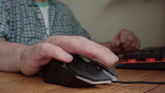 A man's hand working with a computer mouse on a wooden table